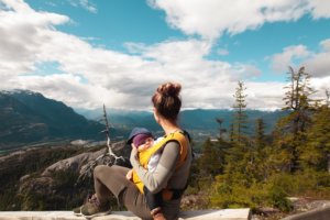 Woman Carrying Baby Sitting On Gray Surface 1157389