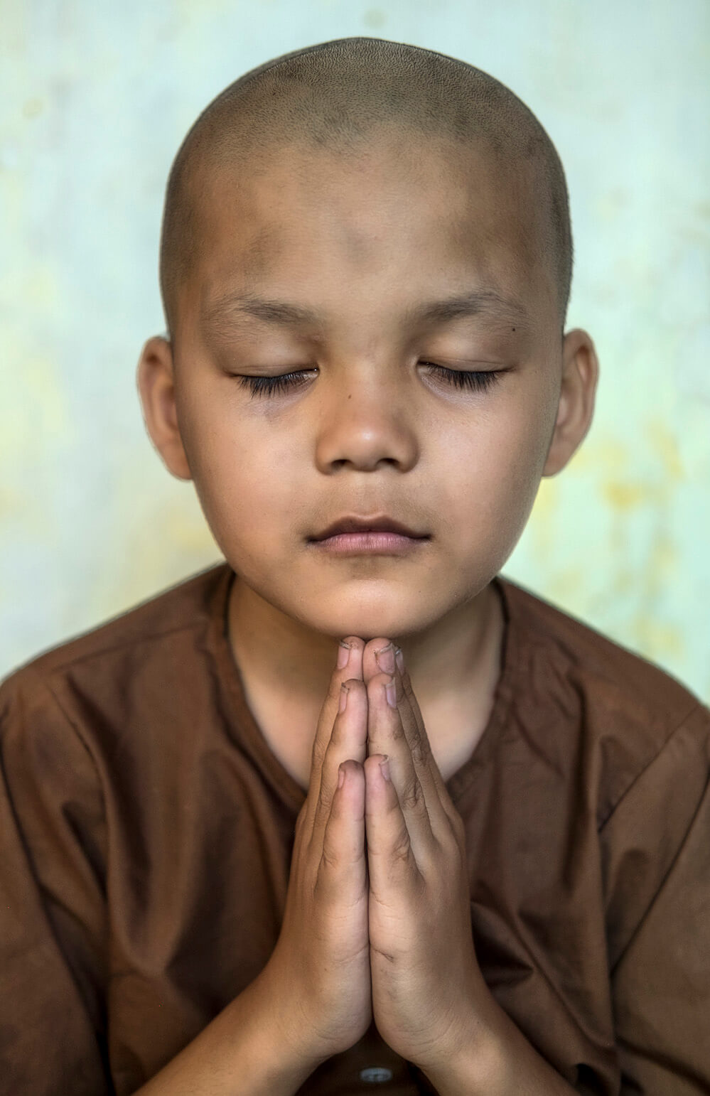 young eight-year-old novice monk Lê Văn Huy praying after doing his morning chores. The dust and grime very visible on his face and fingernails. 
(Photography In a small place of worship 20km west of Hue Vietnam)