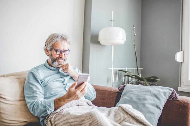 A mature man is in her modern apartment using a mobile phone