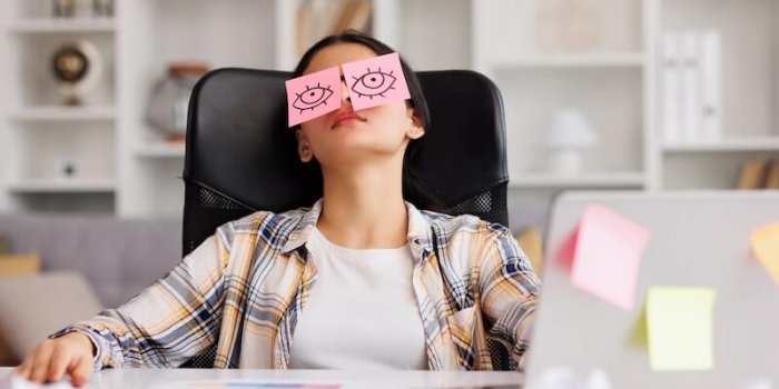 The Concept Of A Lot Of Work. Tired Indian Student Girl Sleeping With Stickers On Her Eyes While Sitting At The Table. Distracted Woman In Home Office