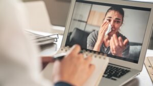Female Psychologist Calms Down Emotional Crying Woman Patient By Video Call On Computer